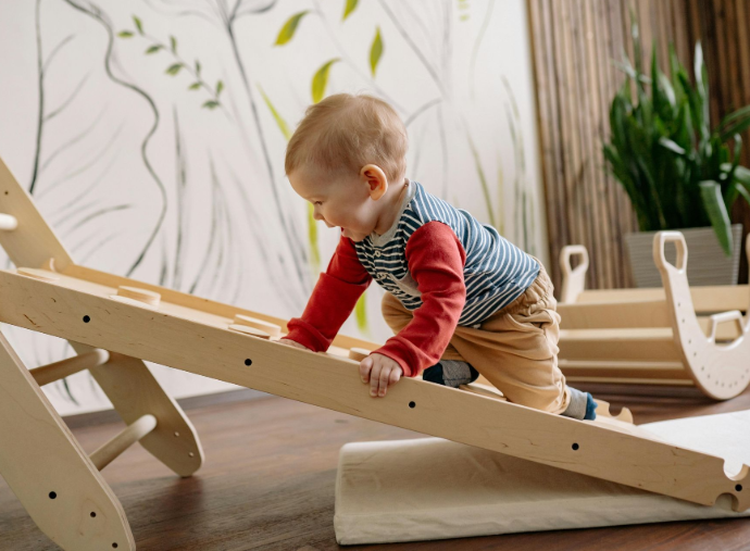 Bébé en train d'escalader un plan en bois en motricité libre